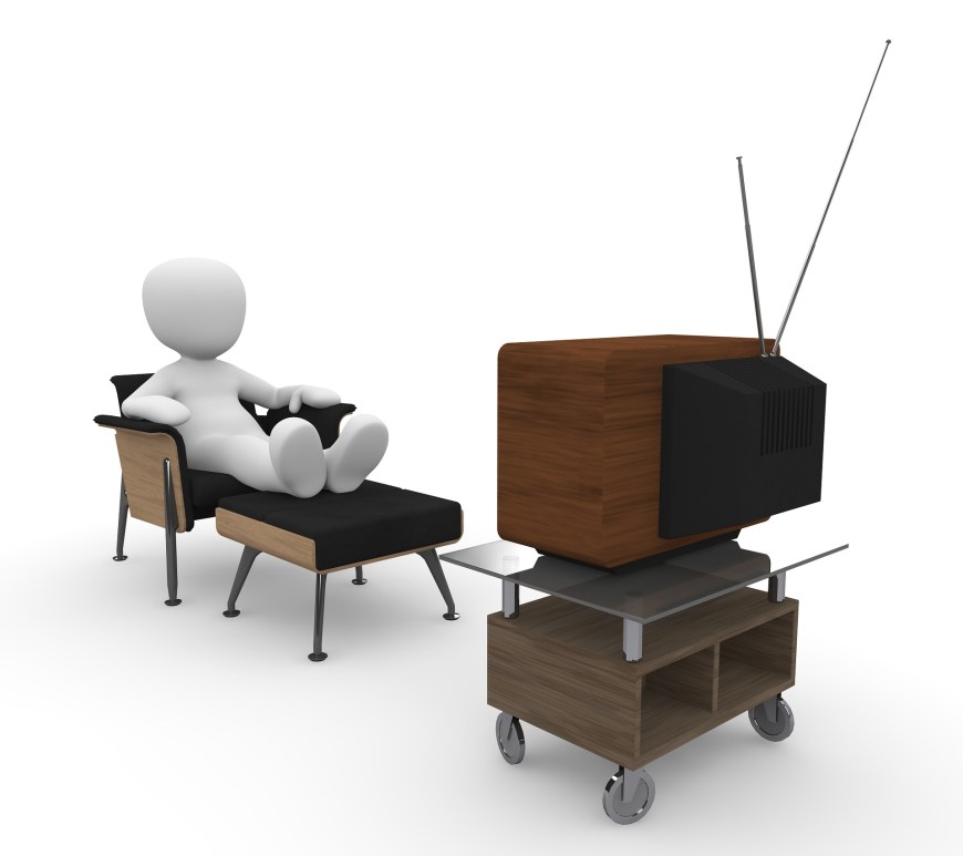 figure seated in an armchair and ottoman, watching TV.